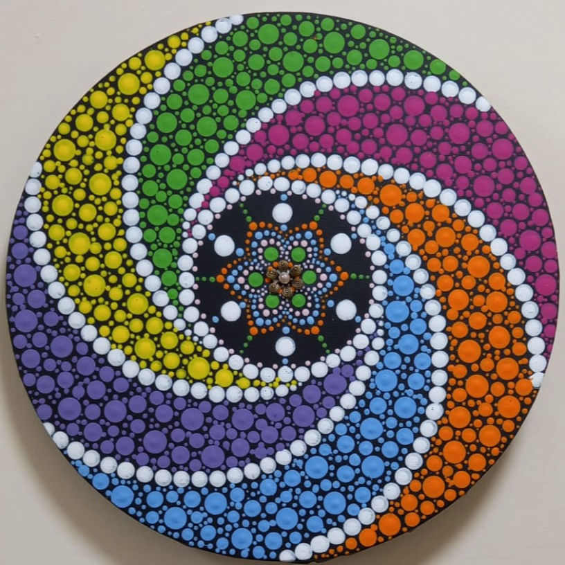 Vibrant mandala with swirling spirals of dots in yellow, green, purple, blue, and orange on black. Central starburst pattern adds harmony.